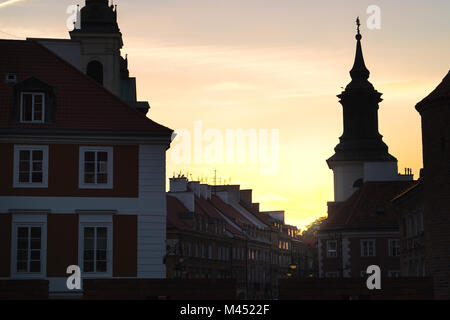 Sonnenuntergang und Sonnenaufgang in der Altstadt von Warschau, Polen. Alte Gebäude in dunklen Schatten, fast Silhouette. Schöne gelbe orange sky. Stockfoto