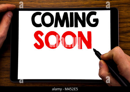 Handschrift Ansagetext angezeigt, die bald kommen. Business Konzept für Nachricht Zukunft geschrieben Tablet , Holz- Hintergrund mit Geschäftsmann Hand, Stockfoto