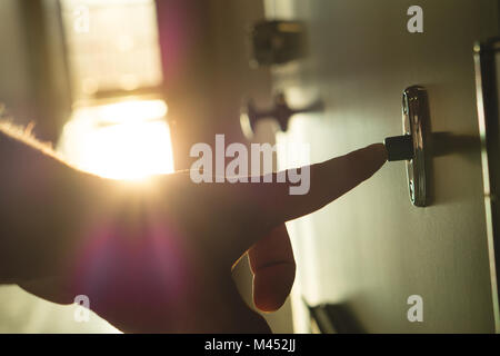 Finger, mit türklingel in sonnige Wohnung Gebäude Flur. Nahaufnahme der Hand läutenden Türglocke in einem Mehrfamilienhaus. Sonnenlicht und Licht Leck kommen Stockfoto