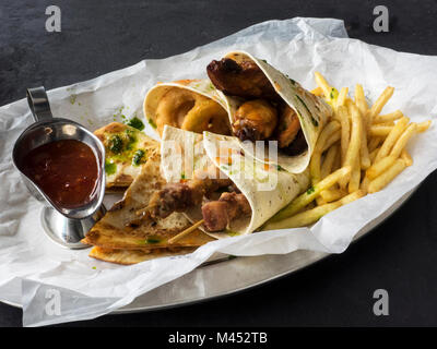 Gebratene Hähnchenkeulen und Filets auf Holzspieße mit Pommes Frites und würzigen Tomatensauce Stockfoto