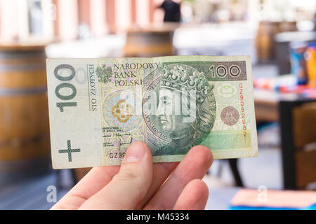 Mann, 100 Polnische Zloty Rechnung im Restaurant im Freien Terrasse. Touristische zeigt ein Hundert Banknote. Stockfoto