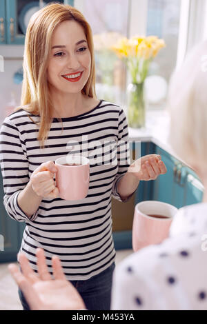 Angenehme Frau trinkt Kaffee mit Mutter in der Küche Stockfoto