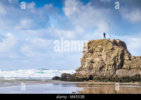 Ein Mann stand an der Spitze der Kapelle Rock Perranporth Strand in Cornwall, England. Stockfoto