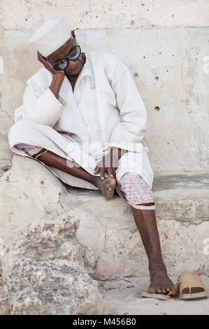 Stone Town, die Insel Sansibar, Tansania, 28.05.2015. Alte Mann der schläft gegen die Wand in der Stone Town, die Insel Sansibar, Tansania sitzen. Stockfoto