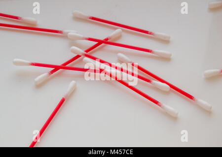 Wattestäbchen liegen auf einem weißen Hintergrund. Aus rotem Kunststoff sticks für Hygiene Stockfoto