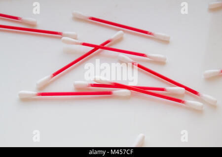 Wattestäbchen liegen auf einem weißen Hintergrund. Aus rotem Kunststoff sticks für Hygiene Stockfoto