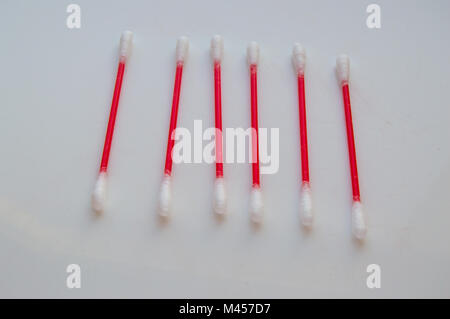 Wattestäbchen liegen in den Zeilen auf einem weißen Hintergrund. Aus rotem Kunststoff sticks für Hygiene Stockfoto