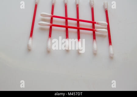 Wattestäbchen liegen in den Zeilen auf einem weißen Hintergrund. Aus rotem Kunststoff sticks für Hygiene Stockfoto