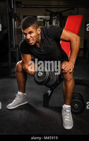 junger Mann tun Bizeps Curl trainieren Sie im Fitness-Studio Stockfoto