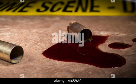 Blut und Messing auf einem braunen Bodenfliesen mit Tatort Band hinter Stockfoto