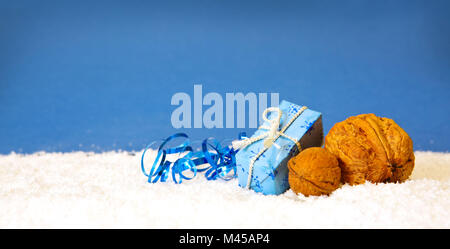 Weihnachten Geschenk und Walnuss auf blauem Hintergrund isoliert. Stockfoto