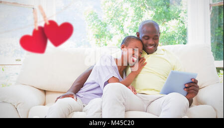 Zusammengesetztes Bild des lächelnden Brautpaar mit Laptop auf couch Stockfoto