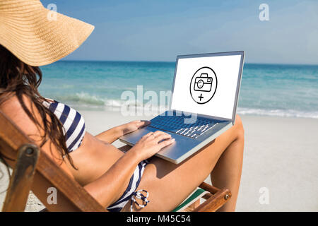 Zusammengesetztes Bild hübsche Brünette mit Laptop auf Liegestuhl Stockfoto