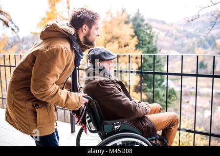 Senior Vater im Rollstuhl und jungen Sohn auf einem Spaziergang. Stockfoto