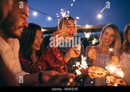 Junge Männer und Frauen genießen mit Feuerwerk. Eine Gruppe von Freunden mit Wunderkerzen Party im Freien genießen. Stockfoto