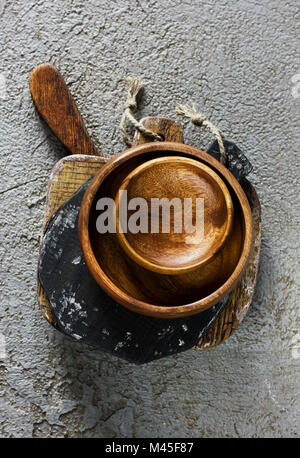 Holzplatten und Schüssel auf grauem Beton Hintergrund. Requisiten für Essen Fotografie Stockfoto