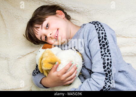 Süße kleine Mädchen umarmte ihre Spielzeug liegend auf Bett Stockfoto