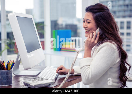 Lächelnden Asiatin auf Anruf mit computer Stockfoto