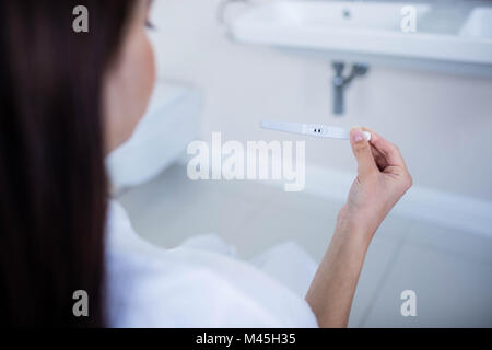 Über Schulter Blick auf Frau betrachten ihr Schwangerschaftstest Stockfoto