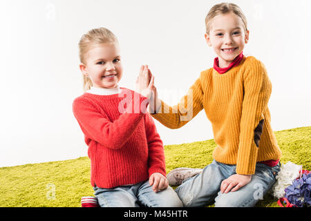 Kleinen Schwestern hoch fünf weißen sitzen auf dem Boden zusammen isoliert auf weißem geben Stockfoto