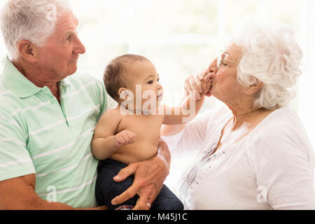 Glückliche Großeltern mit ihrem Enkel spielen Stockfoto