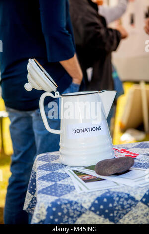 Eine weiße Altmodische, Keramik und Metall Kaffeekanne als Spende Sammelbehälter zu einem Charity Funktion dient. Stockfoto