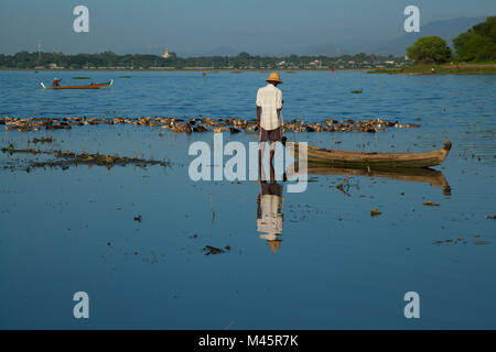Ente Landwirt hearding Enten im See in der Nähe der hölzernen Brücke U-Bein Brücke über den Taungthaman See in der Nähe von Amarapura in Mandalay, Myanmar Stockfoto