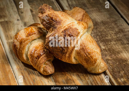 Zwei frisch gebackene Croissants auf hölzernen Tisch. Stockfoto