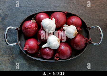 Rote Zwiebeln und Knoblauch in alten Fach auf Schiefer Stockfoto