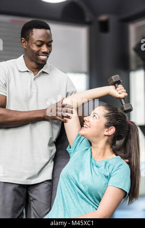 Sportliche Frau Heben von Gewichten von Trainer geholfen Stockfoto