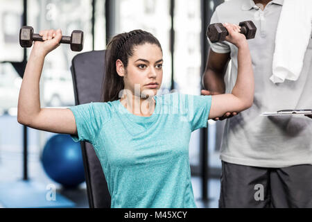 Sportliche Frau Heben von Gewichten von Trainer geholfen Stockfoto