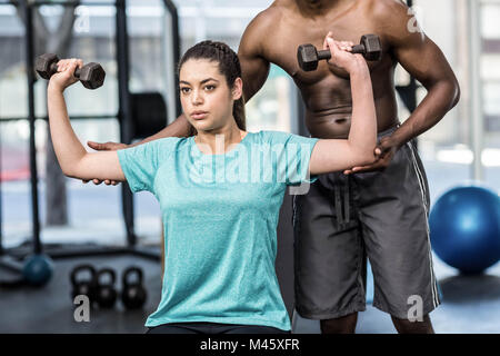 Sportliche Frau Heben von Gewichten von Trainer geholfen Stockfoto