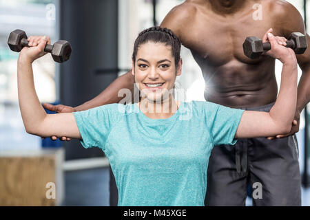 Sportliche Frau Heben von Gewichten von Trainer geholfen Stockfoto