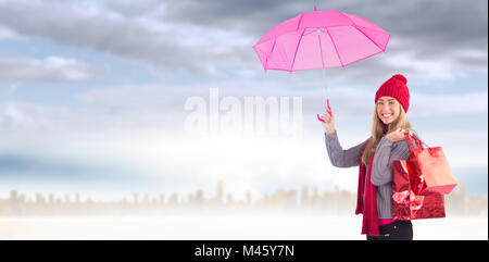 Zusammengesetztes Bild von festlichen blonde Holding Regenschirm und Taschen Stockfoto