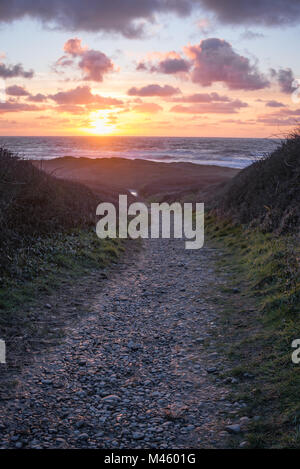 Kiesweg hinab zum Widemouth Bay bei Sonnenuntergang. Stockfoto