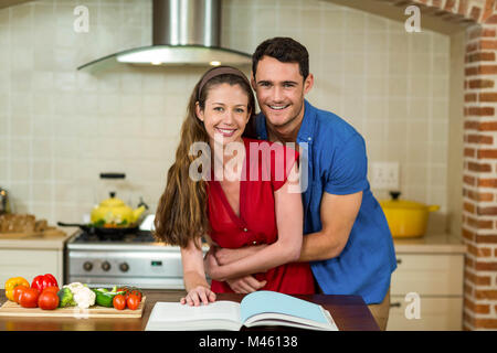 Paar, umarmen, während der Überprüfung des Rezeptbuch Stockfoto