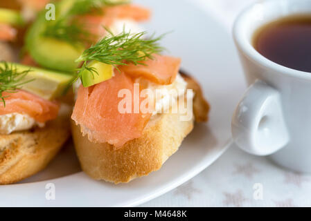 Bruschetta, snack-Sandwiches mit weißer Käse, geräuchertem Lachs und Stücke von Avocado dekoriert von Dill. Stockfoto