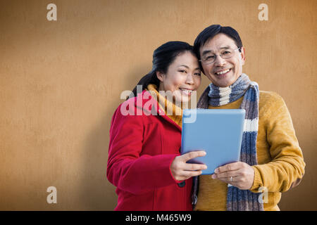 Zusammengesetztes Bild des asiatischen paar auf Balkon mit tablet Stockfoto