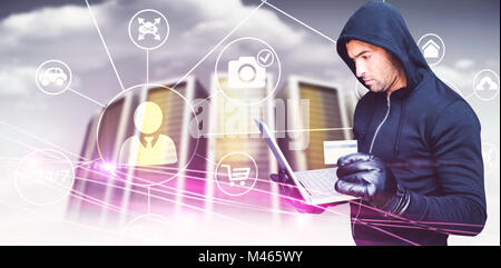 Zusammengesetztes Bild der Hacker mit Laptop und Credir card Stockfoto