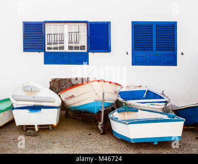 Arrieta, Lanzarote/Spanien: Angeln, Boote an Land vor einem Haus mit weißen Wänden und blauen Fenstern Stockfoto