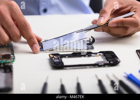 In der Nähe von einem Techniker Hand Reparieren beschädigter Bildschirm auf dem Mobiltelefon Stockfoto