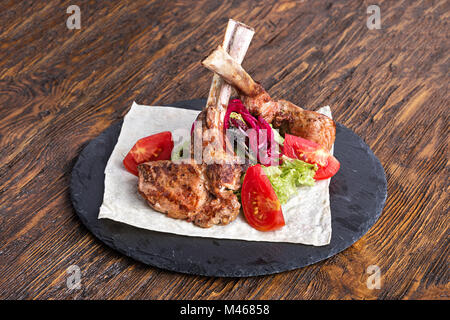 Ribeye Steak auf den Knochen, Tomahawk, serviert mit Tomaten und Eisbergsalat auf pita auf Schiefer. Stockfoto