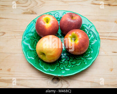 Vier bunte Pink Lady Äpfel Sorte Cripps Pink auf der grünen Platte Stockfoto