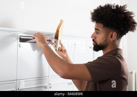 Seitenansicht eines jungen Mannes, Briefe in der Mailbox Stockfoto