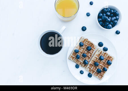 Waffeln und Blaubeeren Frühstück mit Kaffee und Orangensaft Overhead auf weißem Hintergrund Stockfoto