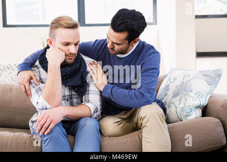 Gay paar trösten einander auf der couch Stockfoto