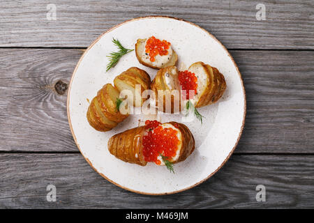 Das Kochen selbst, gebackene Kartoffeln mit Holländischer Sauce und roter Kaviar auf einem Holztisch, Ansicht von oben Stockfoto