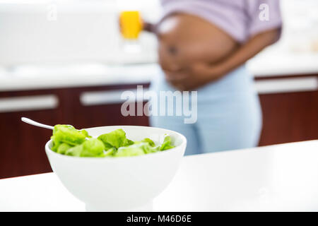 Schwangere Frau in der Küche mit Salat auf Tisch Stockfoto