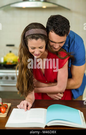 Paar, umarmen, während der Überprüfung des Rezeptbuch Stockfoto