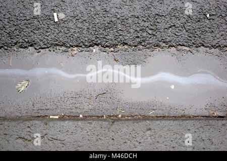 Einen Ölfilm oder Öl trail auf dem nassen Asphalt der Straße. Stockfoto